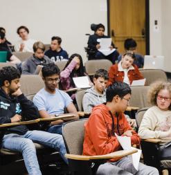 Students talk in pairs in a small lecture hall.