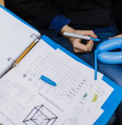 A student uses a pen to write on a balloon during a 3-dimensional object activity.